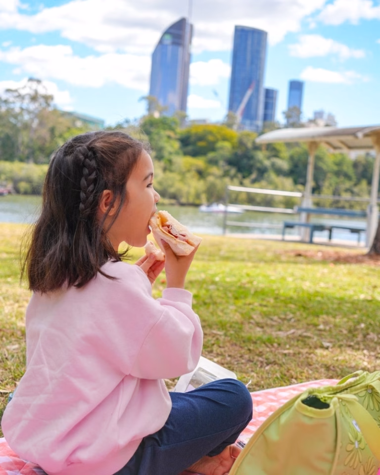 Child eating a sandwich during a picnic at Kangaroo Point Cliffs Lookout