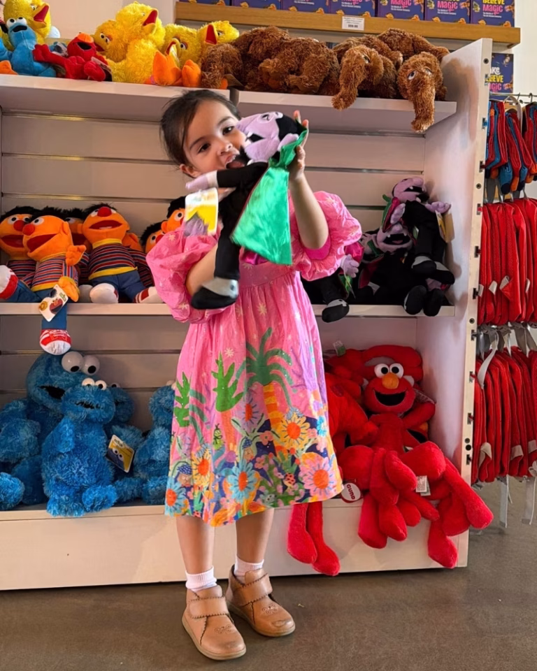 A young girl holding a Count Von Count plush toy at the QAGOMA store