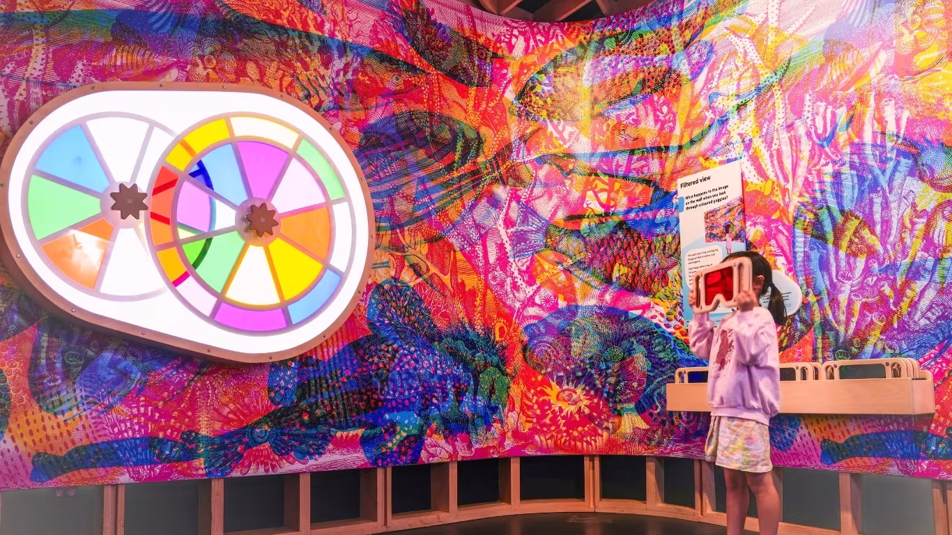 Child looking through a colour filter exhibit at SparkLab, Queensland Museum