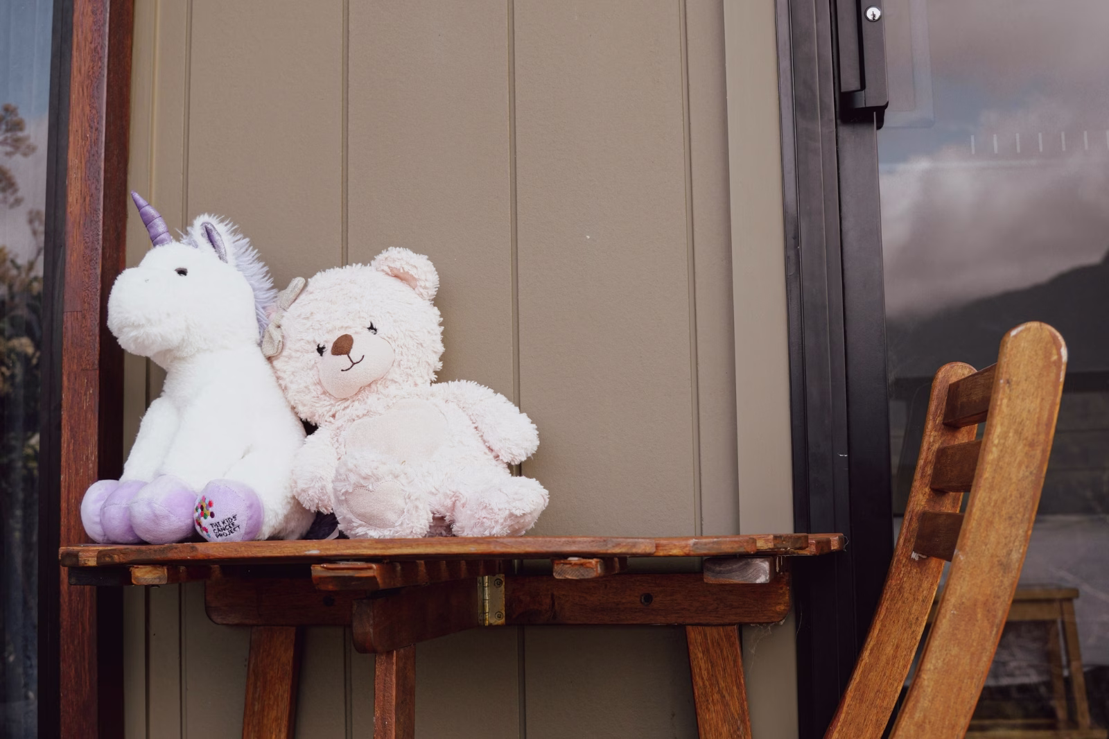 A teddy bear and toy unicorn sitting on the verandah table at Widgee Cottage, Worendo Cottages, Scenic Rim accommodation for families