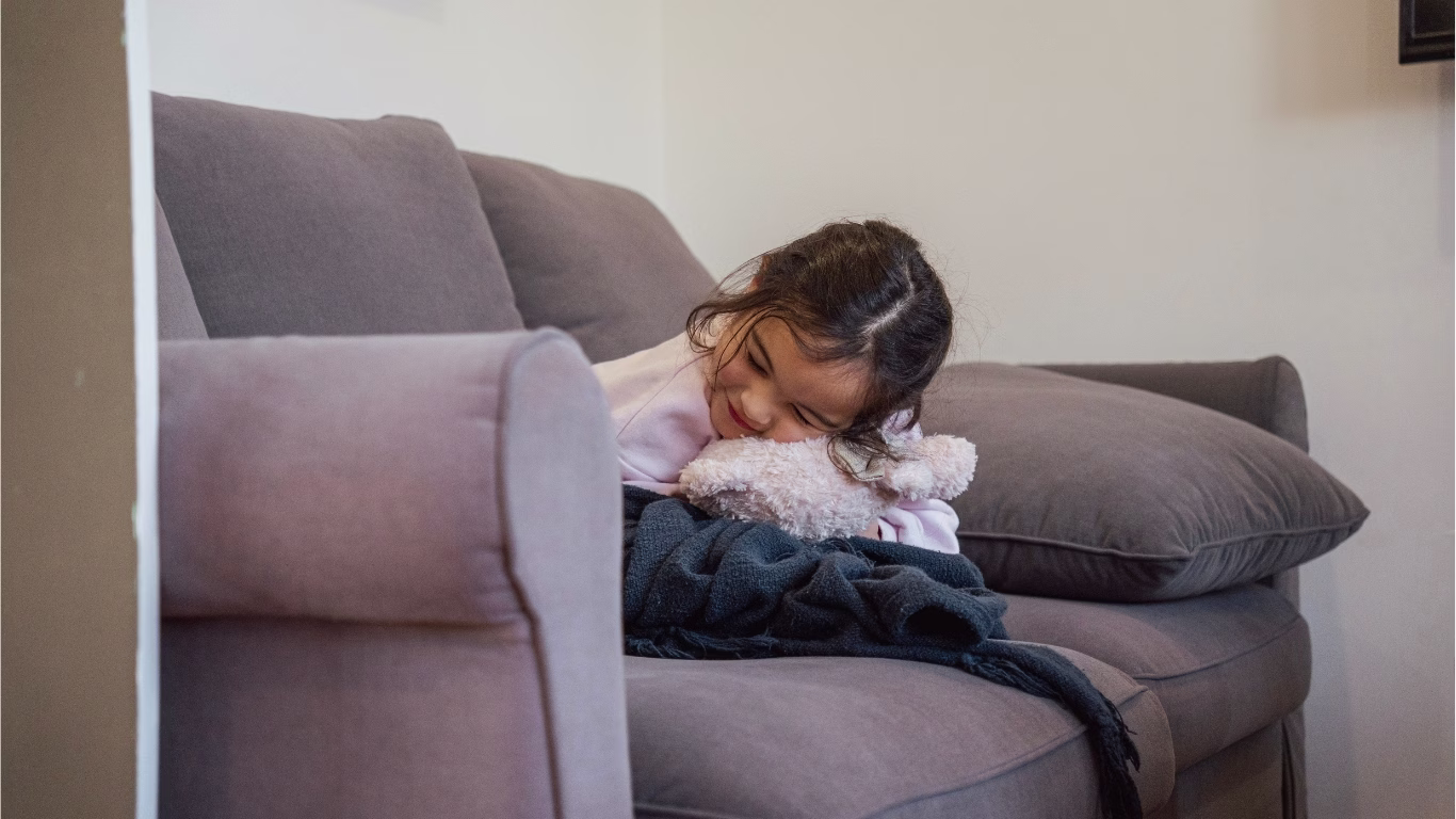 Young girl cuddling her teddy bear on the sofa bed in Widgee Cottage, Scenic Rim family accommodation at Worendo Cottages